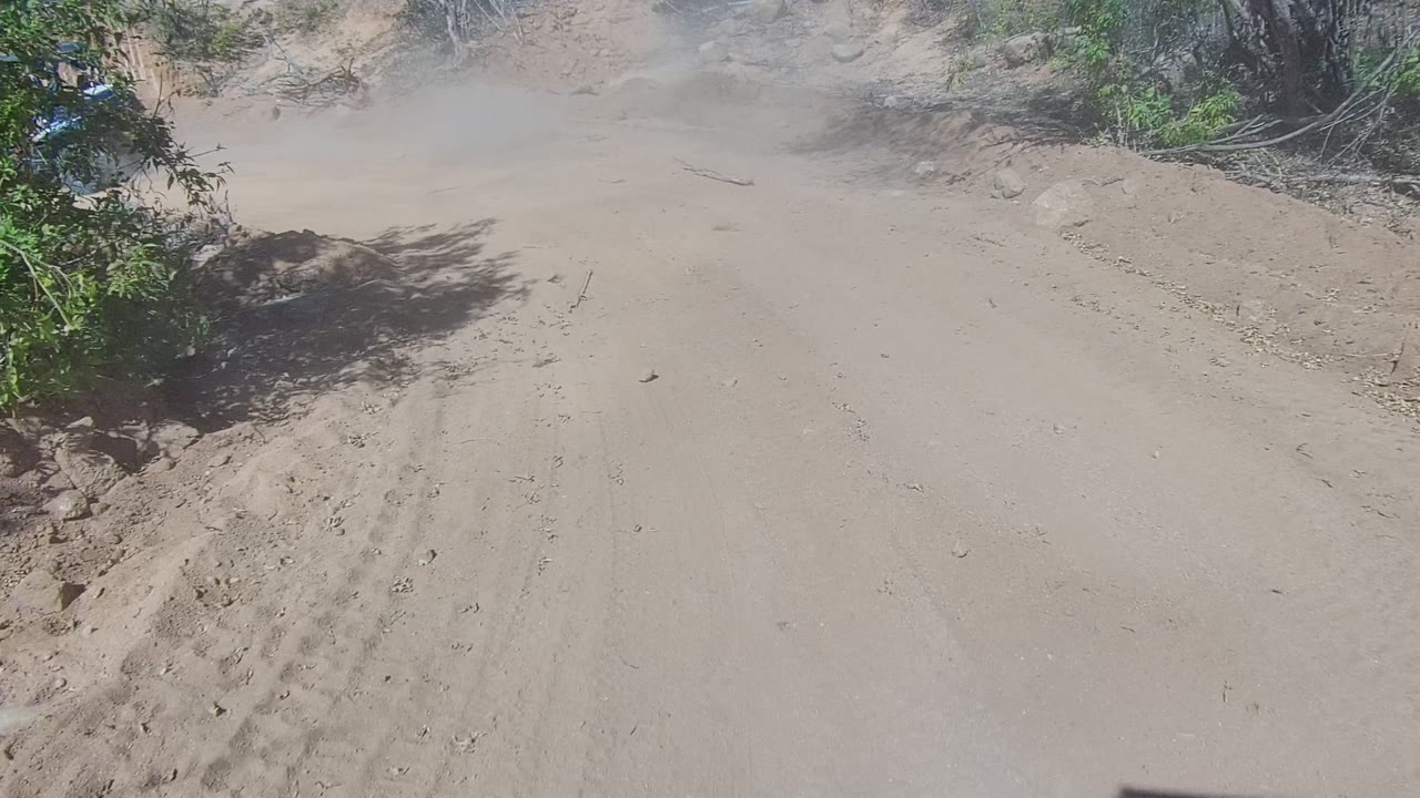 A sandy dirt road in Los Cabos, Baja California Sur runs through dry brush with dust over the track and no visible people.