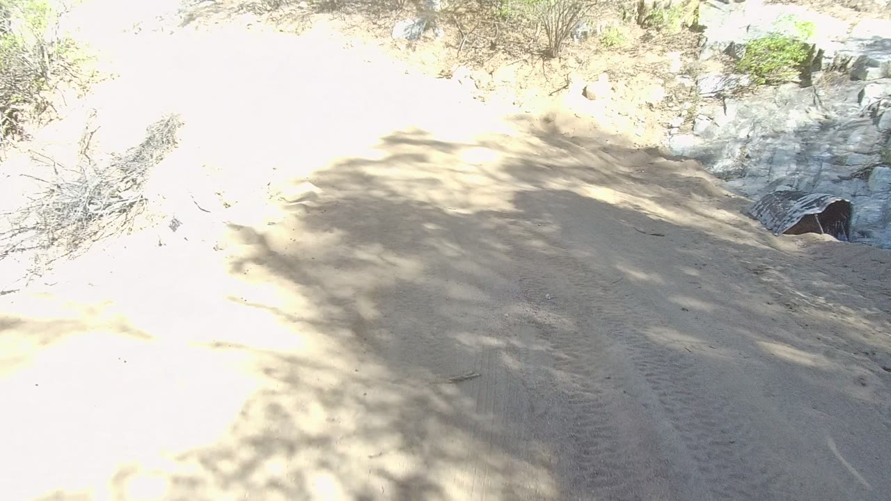 Bright sandy road with shadow patches and rocky edge