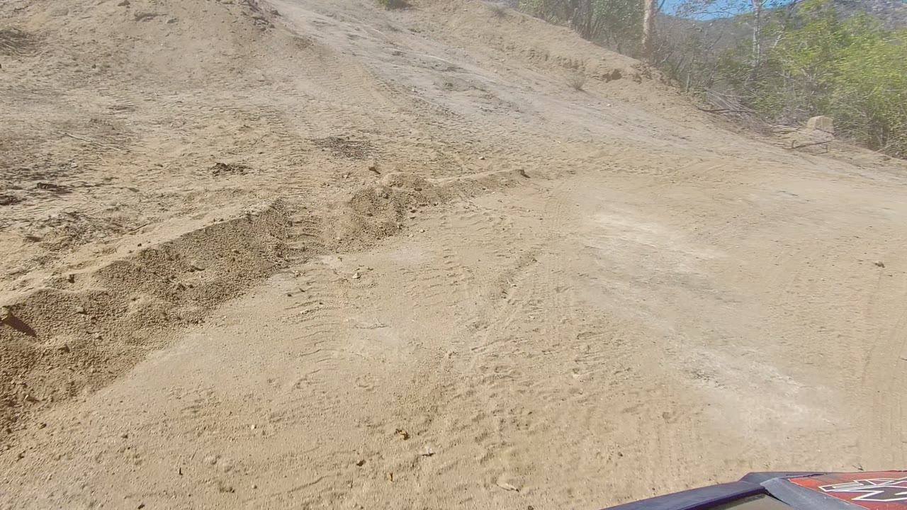 Uneven sandy track beside a cut dirt bank