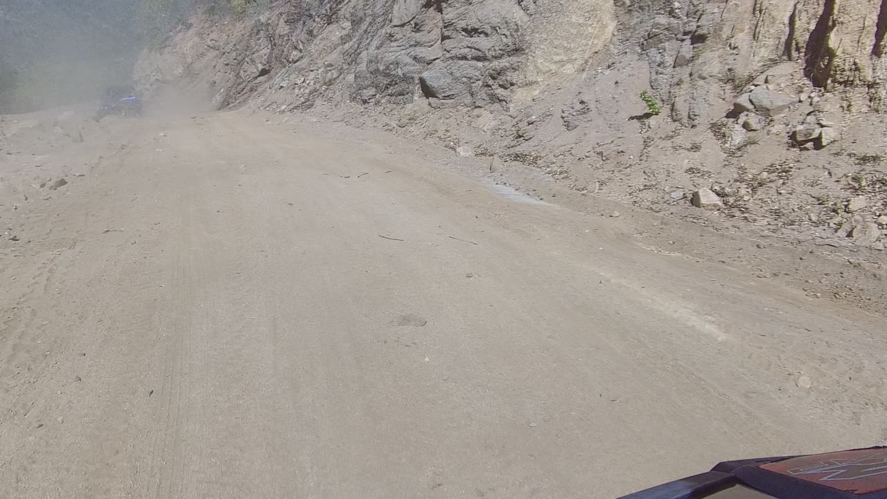 Rocky dirt track with dust drifting across the road