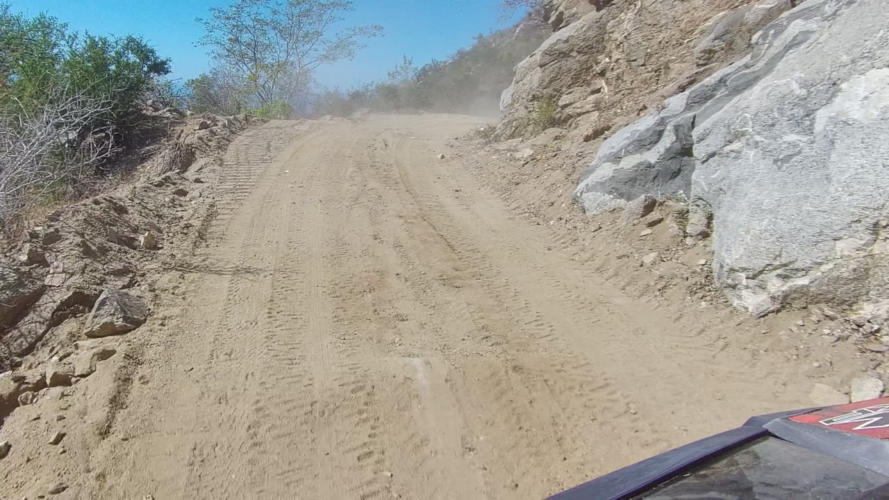 Dusty dirt track curving through rocks and sparse shrubs
