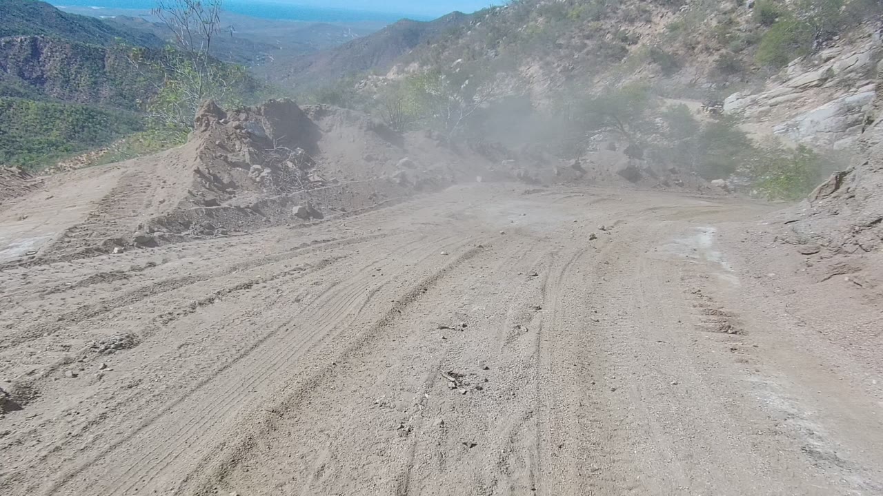 Rocky dirt road with dust haze and pale cliff face