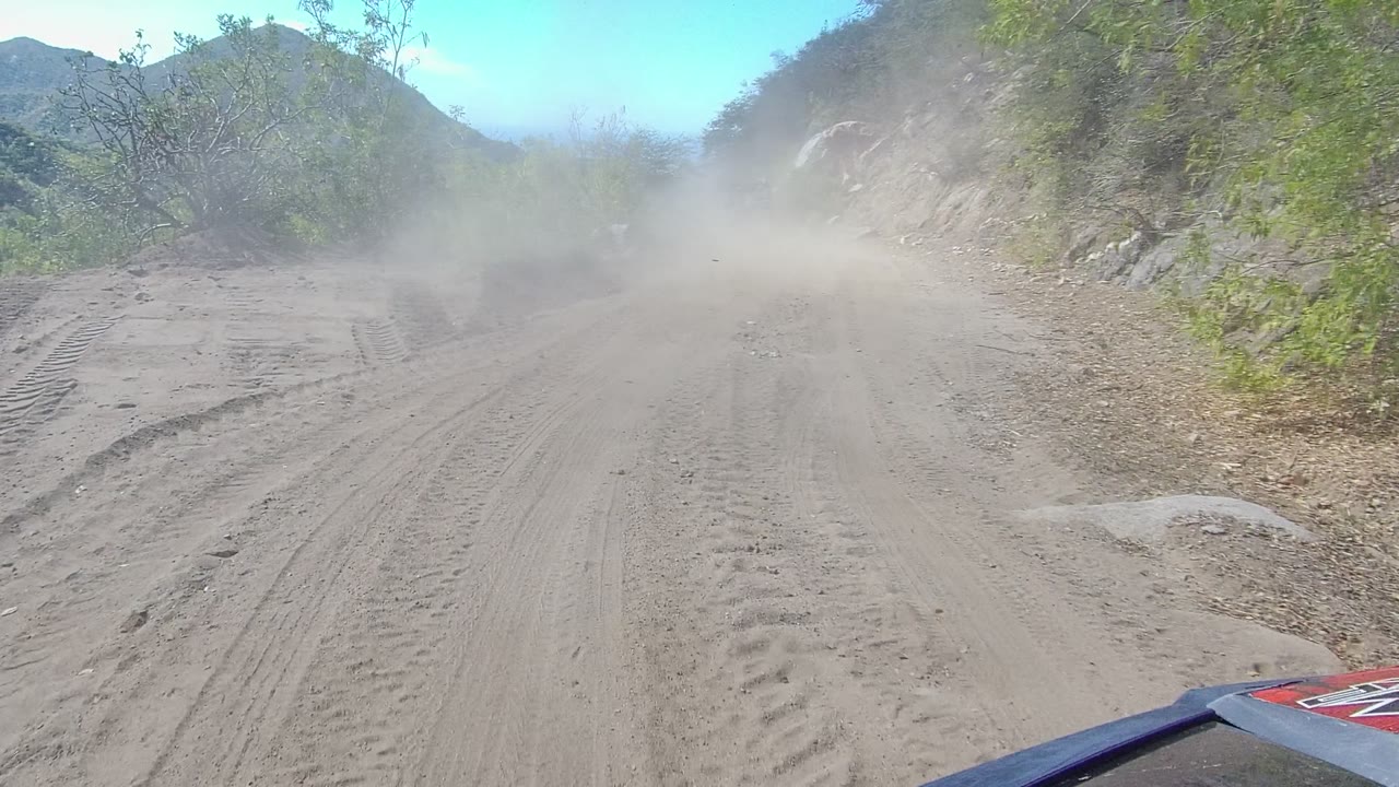 Forward road view with dust cloud and vehicle edge