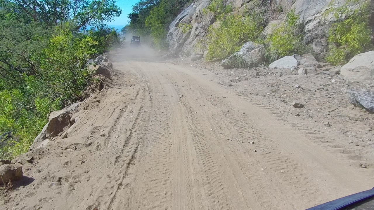 Rocky mountain dirt road with dust ahead
