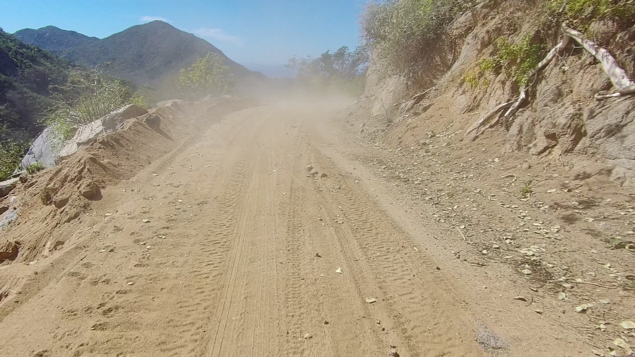 Sandy mountain road with dust and roadside rocks