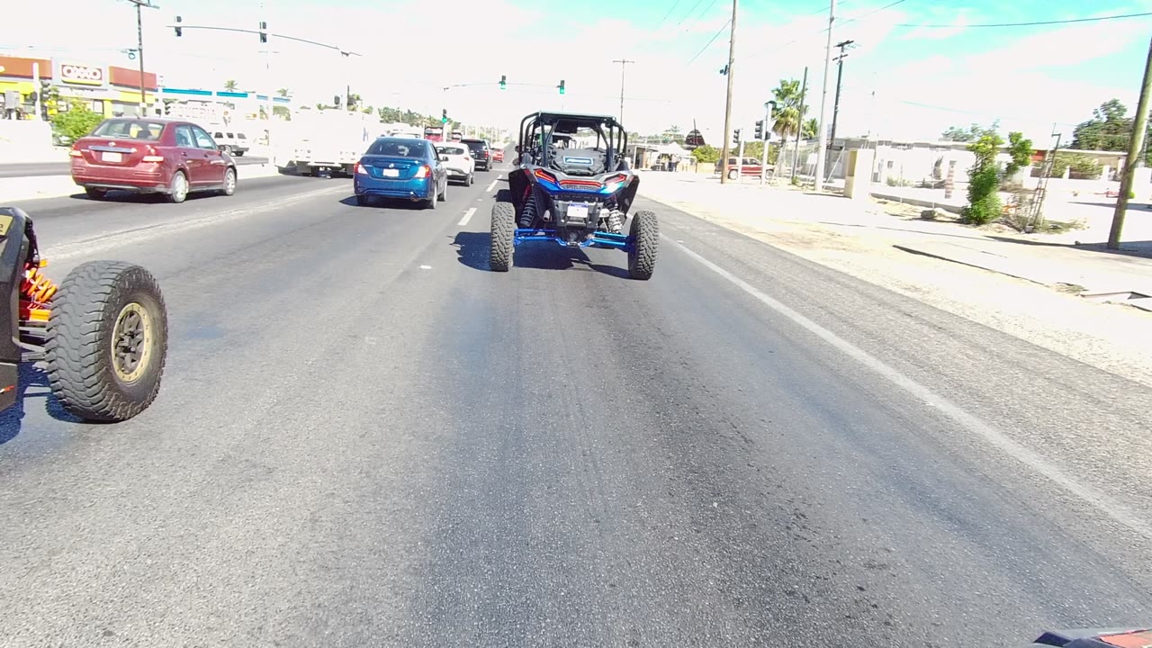 Off-road vehicle and cars approaching a signalized urban intersection.
