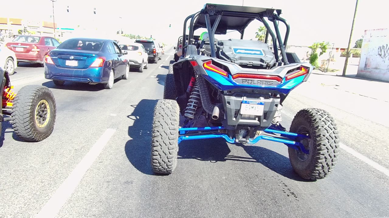Blue and black UTV close to camera with cars moving ahead on the road.