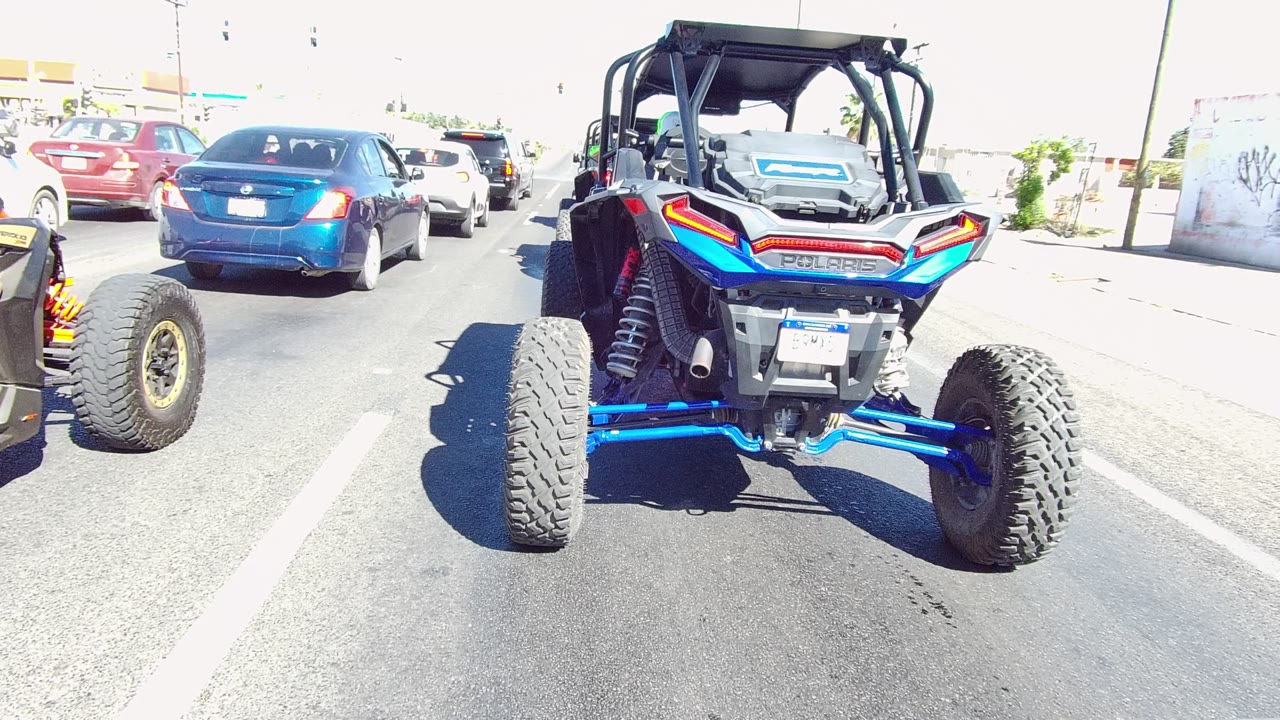 Blue and black UTV following cars on a paved road