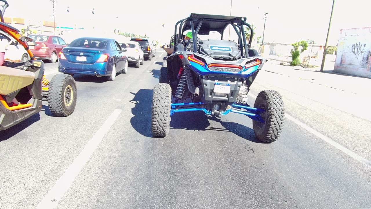 UTV remains centered behind cars with a yellow off-road vehicle partly visible at left.