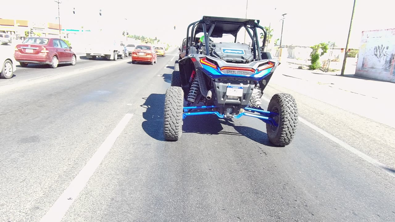 Blue UTV centered behind traffic on a bright road