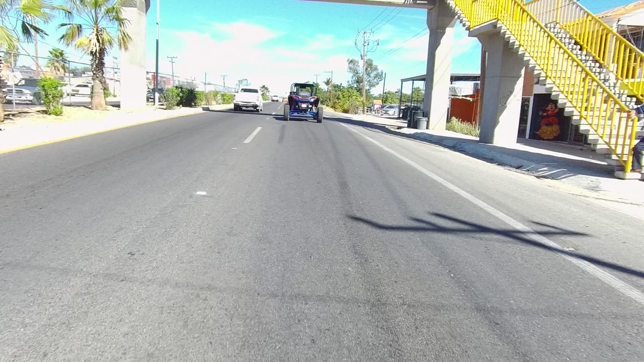 Road-level view beneath the yellow overpass with traffic ahead.