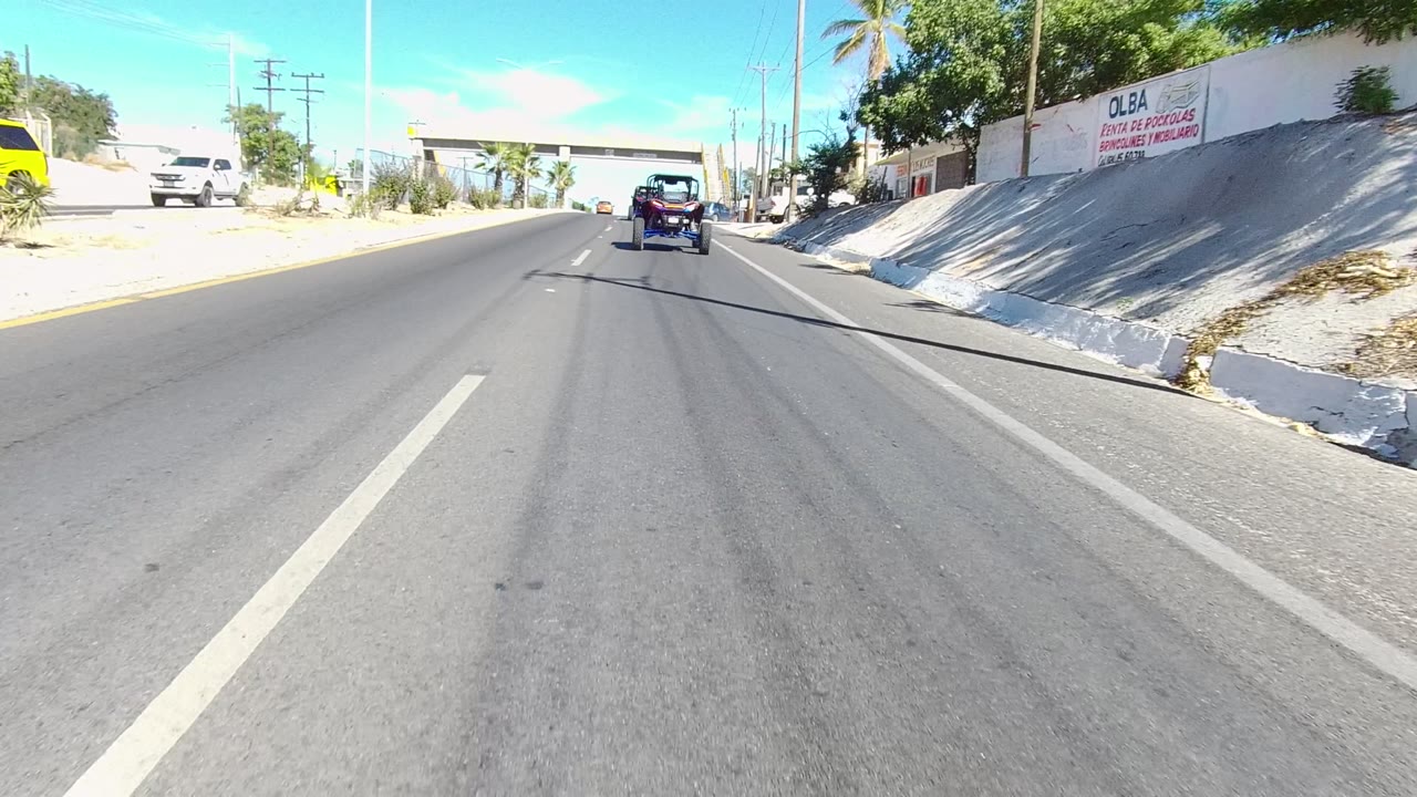 Road scene with a small vehicle ahead and a white pickup near the right curb.