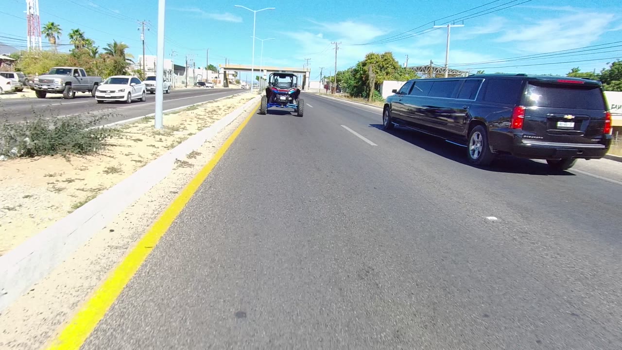 Limousine closer to the right side of the road behind a golf cart.