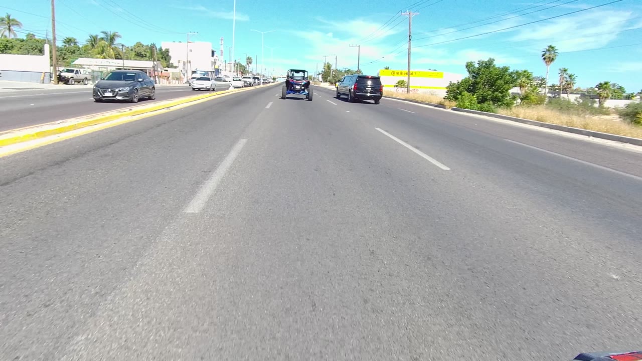 Cars travel on a wide road near a yellow roadside building.