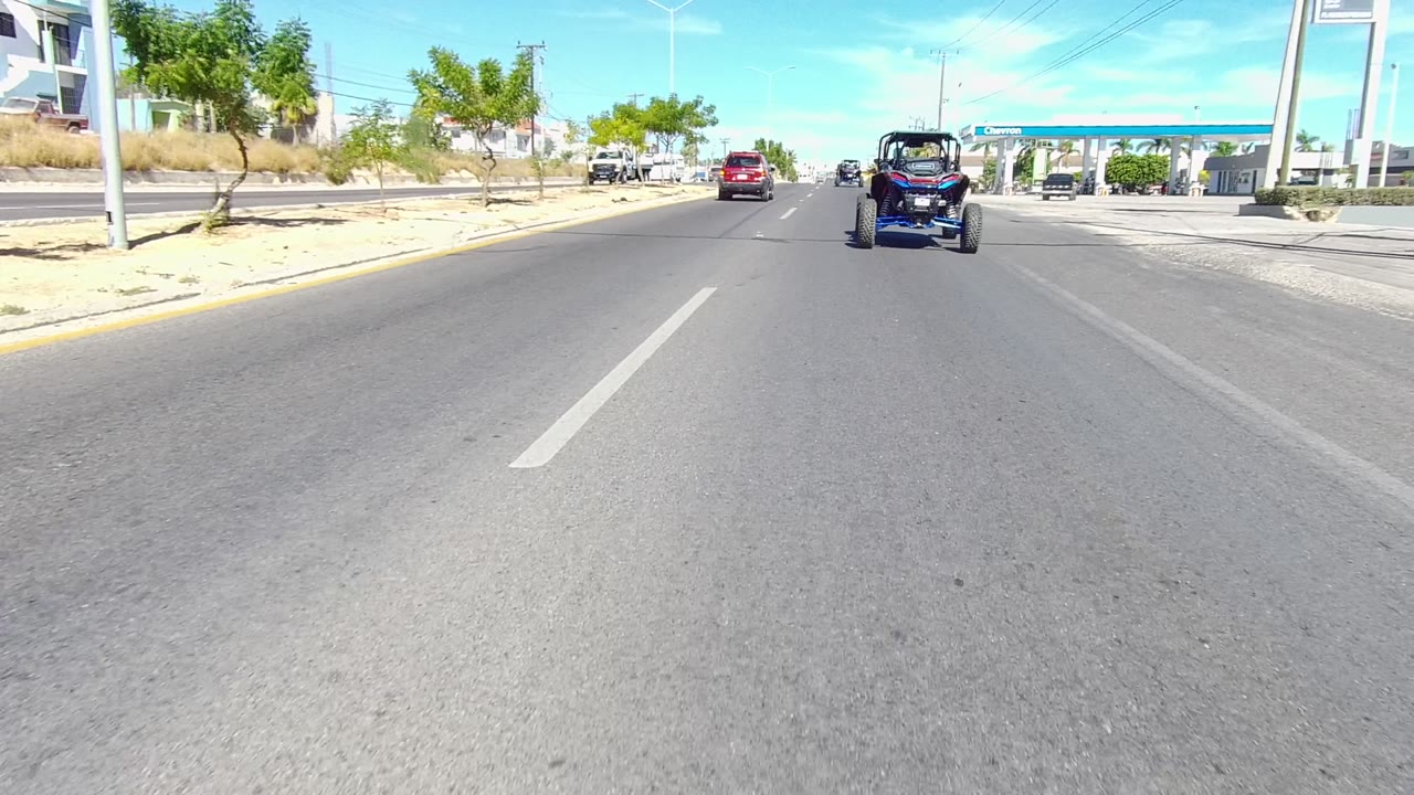Dune buggy and red car on road beside Chevron station