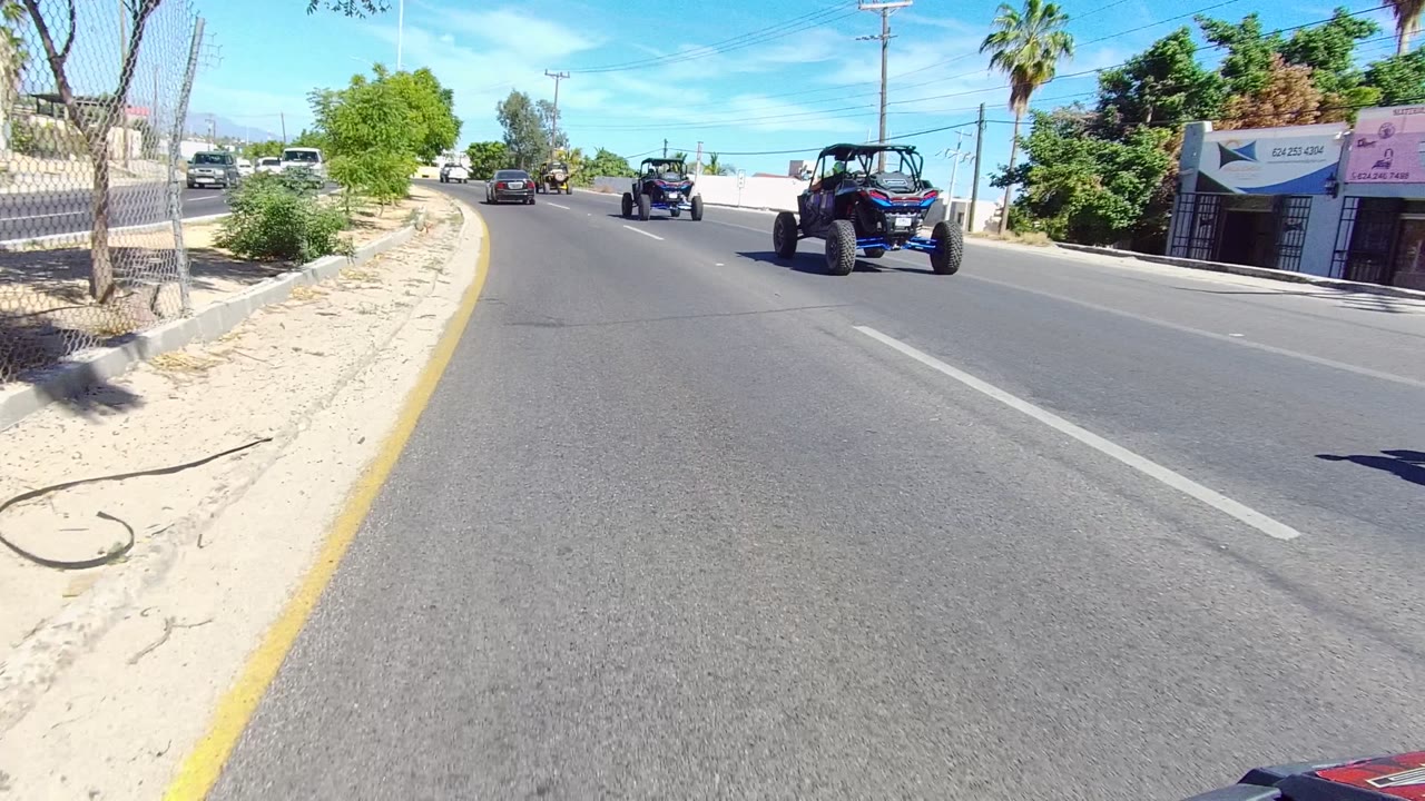 Off-road vehicles continue ahead on a broad curving road.