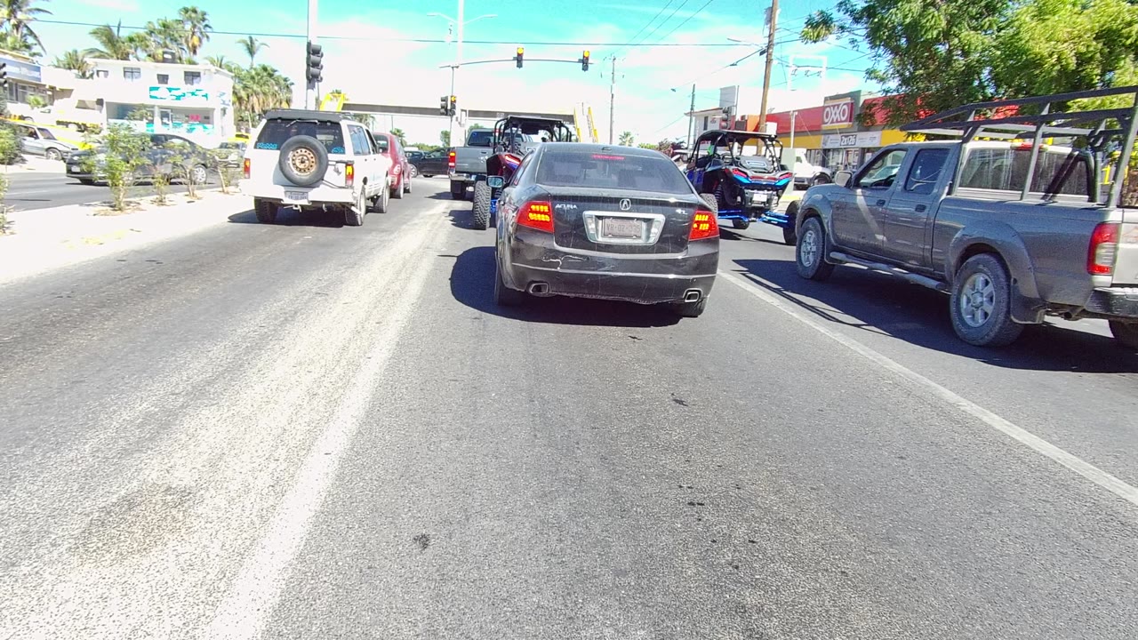 Stopped traffic at a sunlit intersection with SUVs, a sedan, and a pickup truck.