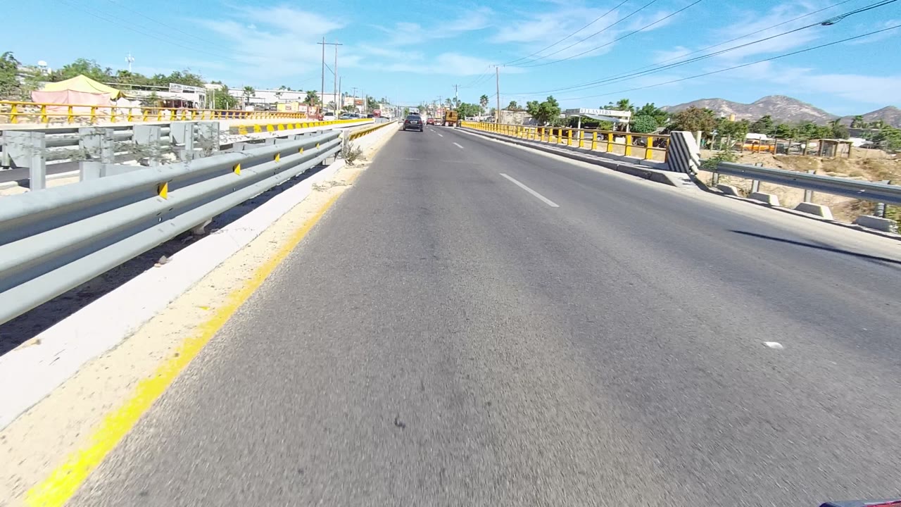 Bridge roadway with mixed gray and yellow guardrails beside traffic.