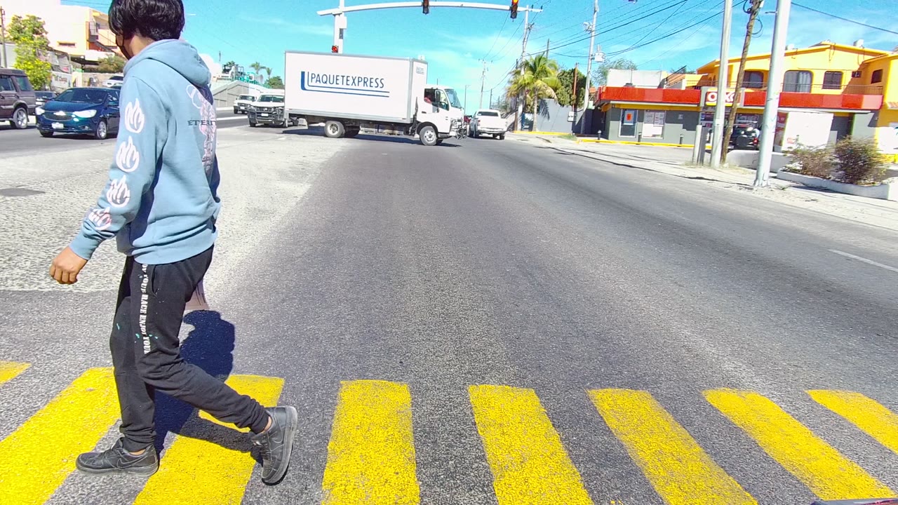 Pedestrian nearing the edge of frame while vehicles wait and move through the intersection.