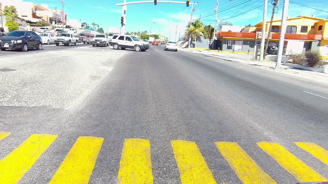 Vehicles pass through the intersection with a yellow crosswalk in front.