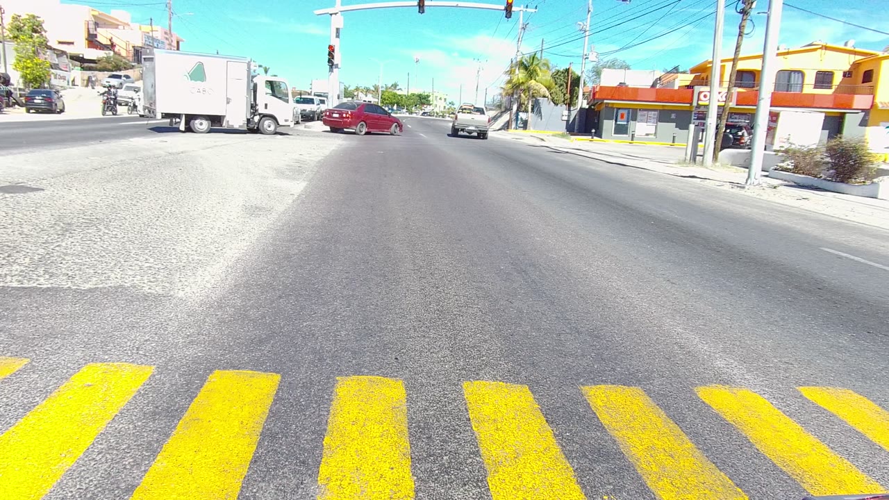 White box truck and red car moving through a bright intersection