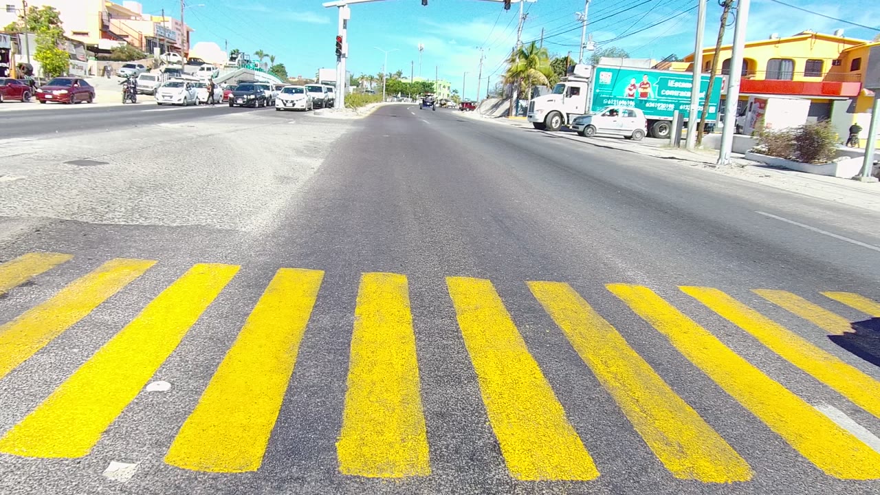 Intersection traffic with yellow crosswalk stripes in the foreground