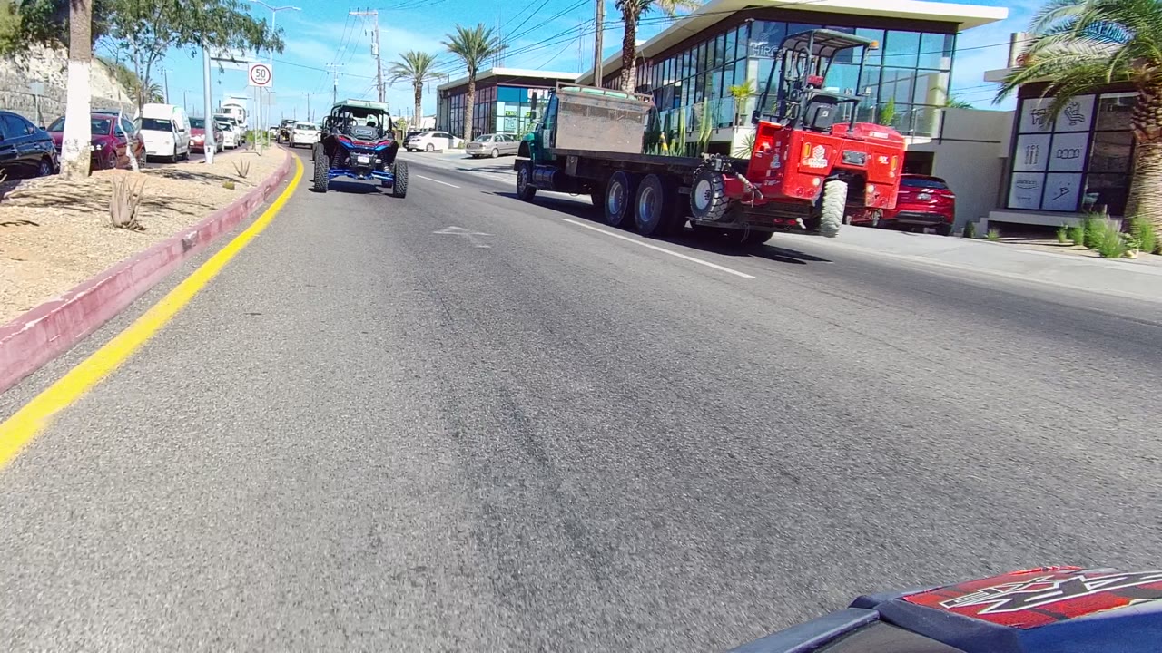 Urban road with dump truck beside storefronts and parked cars