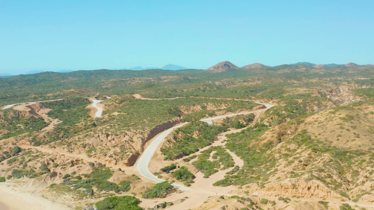 Curved road bordered by rocky tan slopes and scrub vegetation.