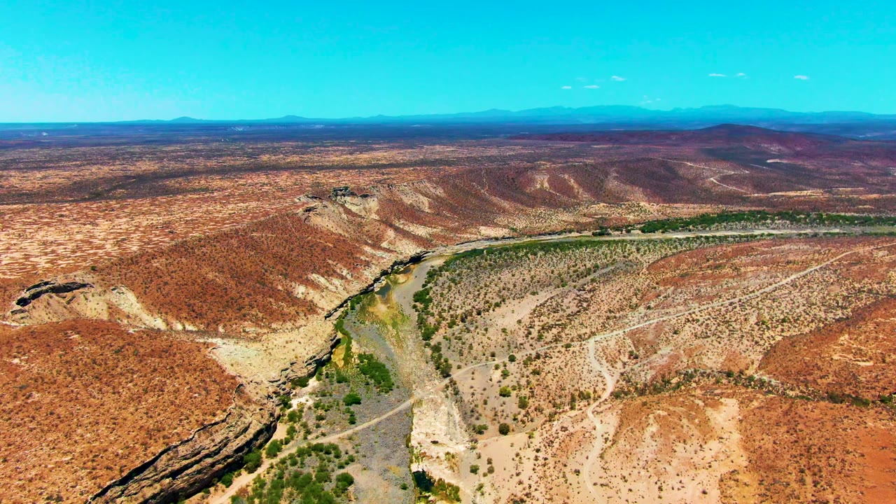 High aerial desert view with a river bend and scrub-covered hills.