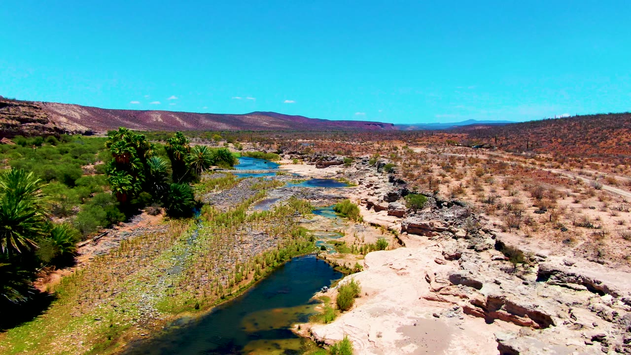 Shallow pools and exposed rocks run through desert scrub.