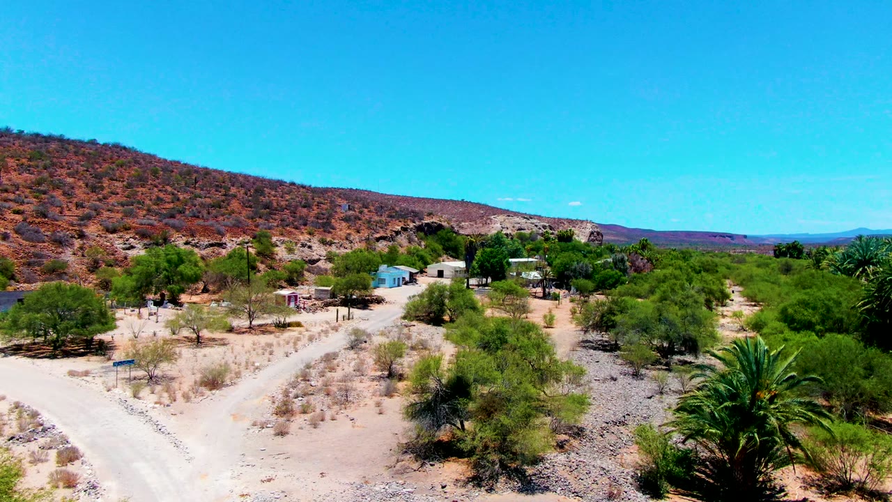 Elevated view of dirt road, desert trees, and small structures
