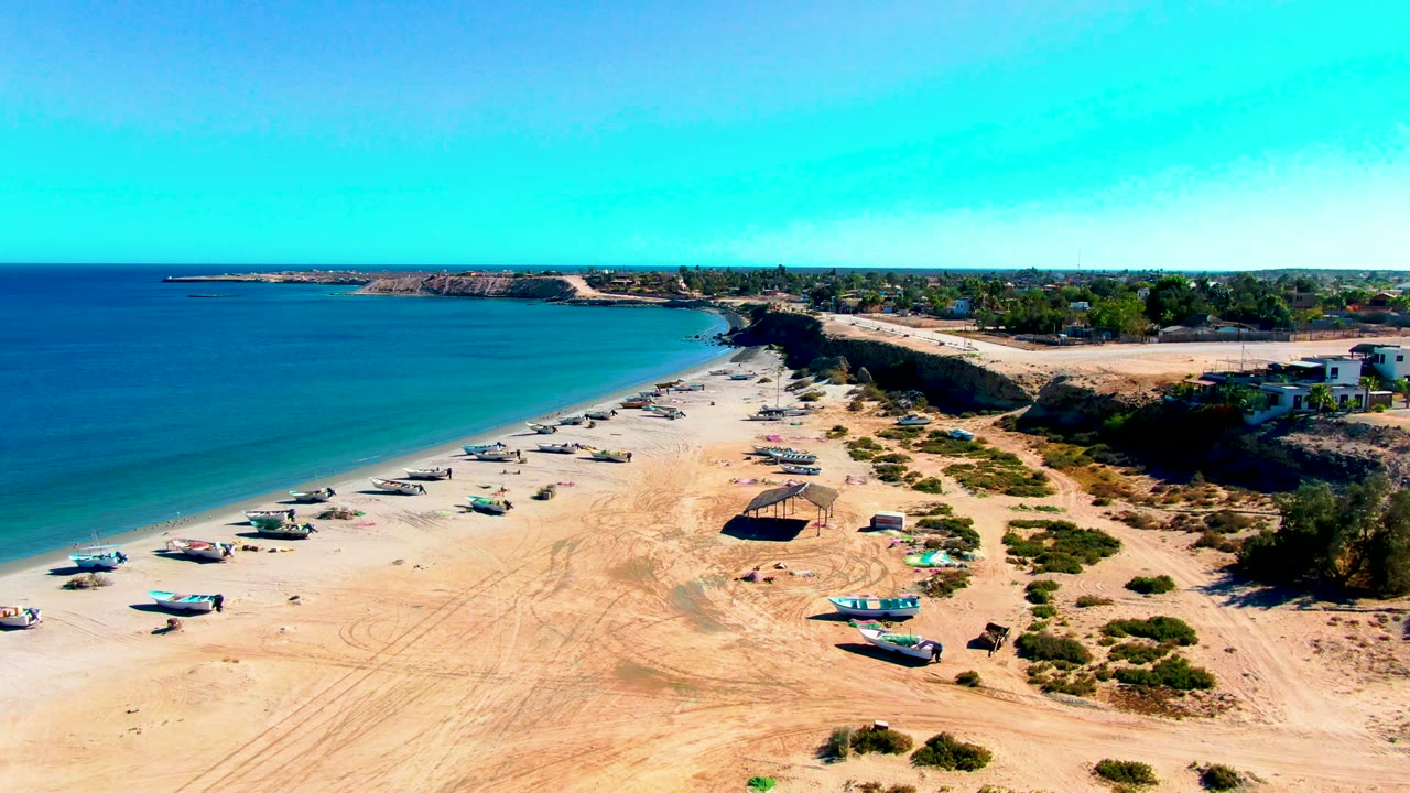 Aerial shoreline with boats, beach shelter, and coastal bluff