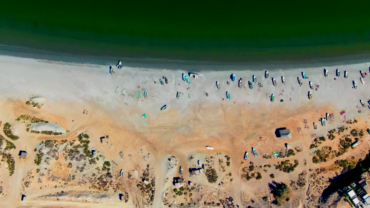 Aerial shoreline with people and beach objects near dunes