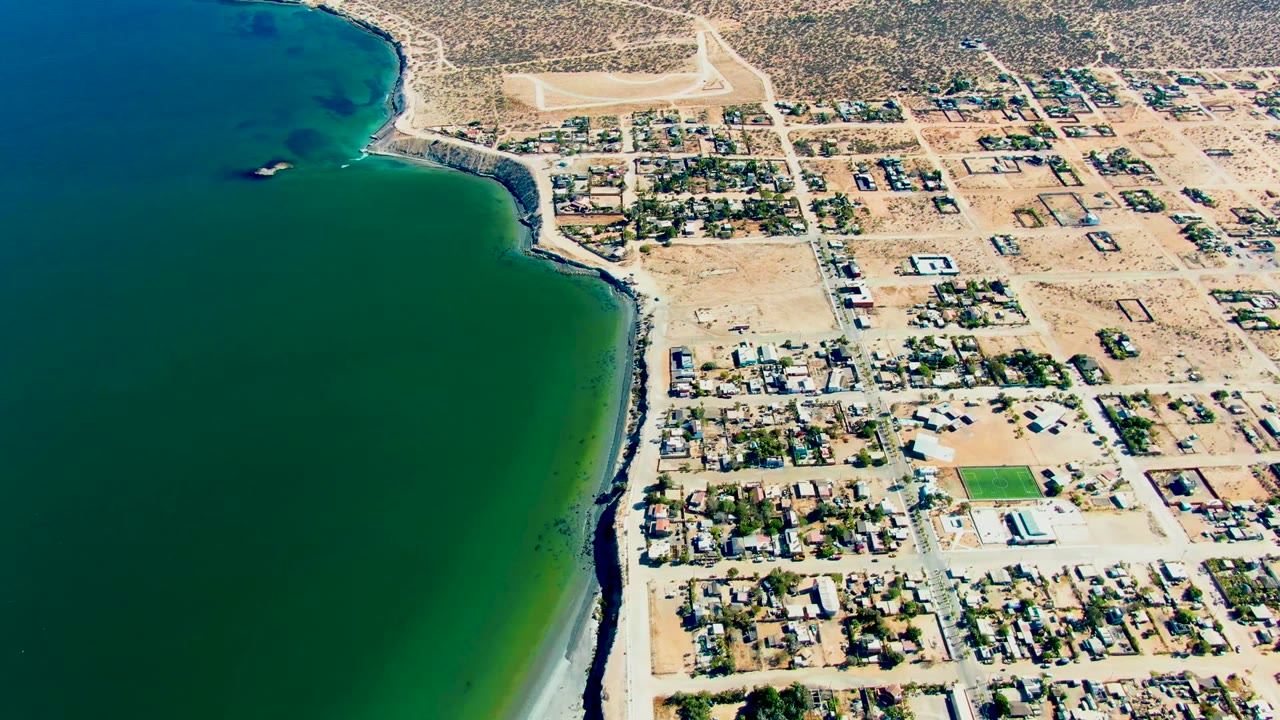 High aerial coastal view with bay water, exposed sand, streets, and houses.