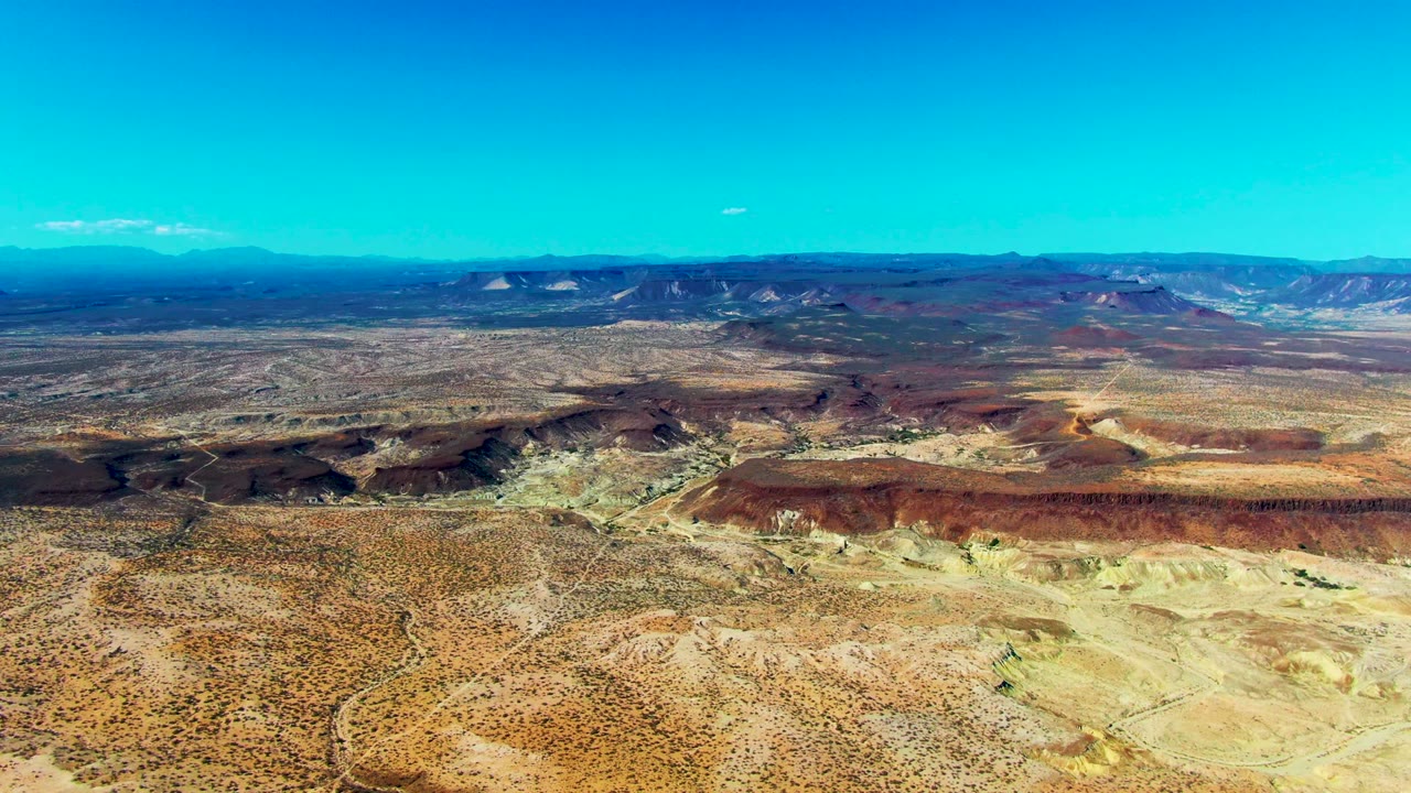 Aerial view across arid terrain and layered mesas.
