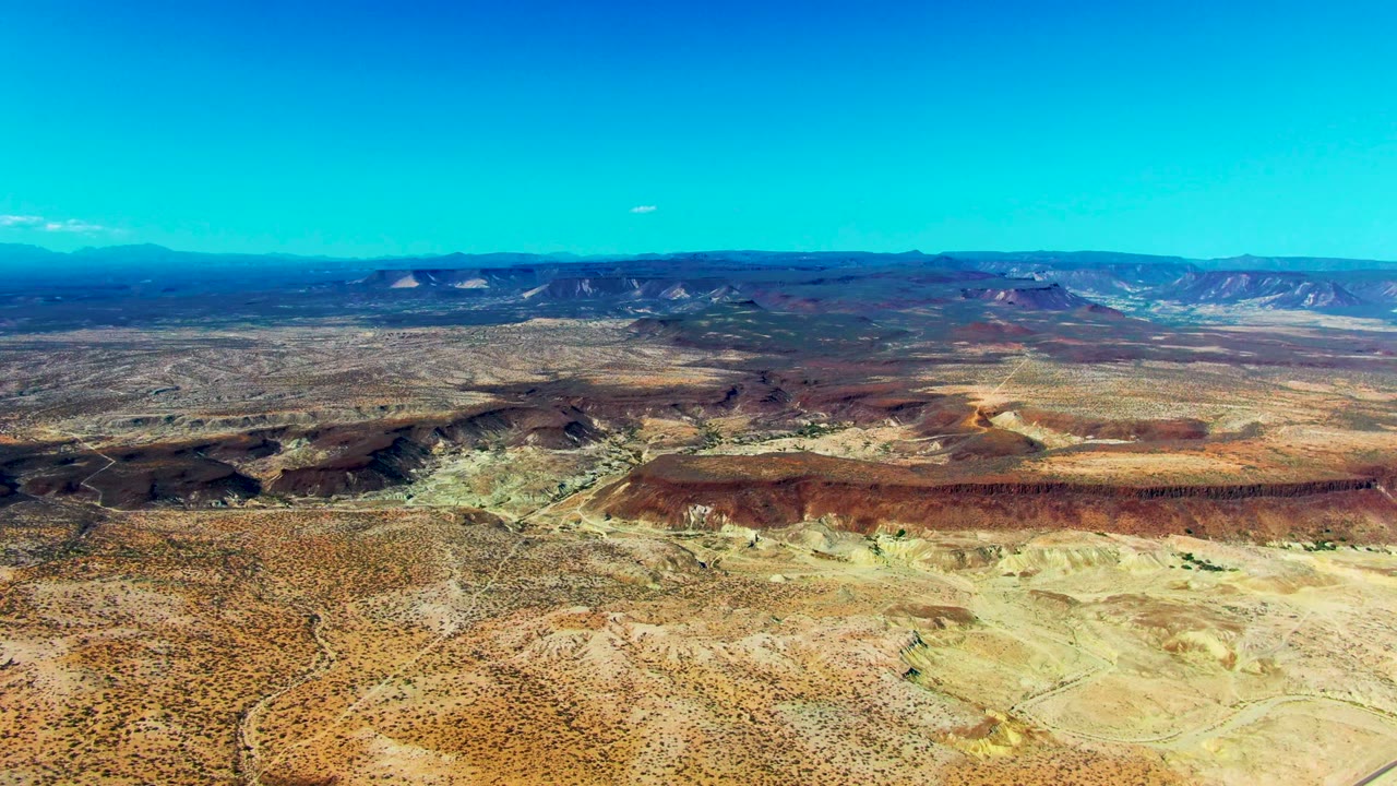 Wide desert plateau with rocky mesas under blue sky