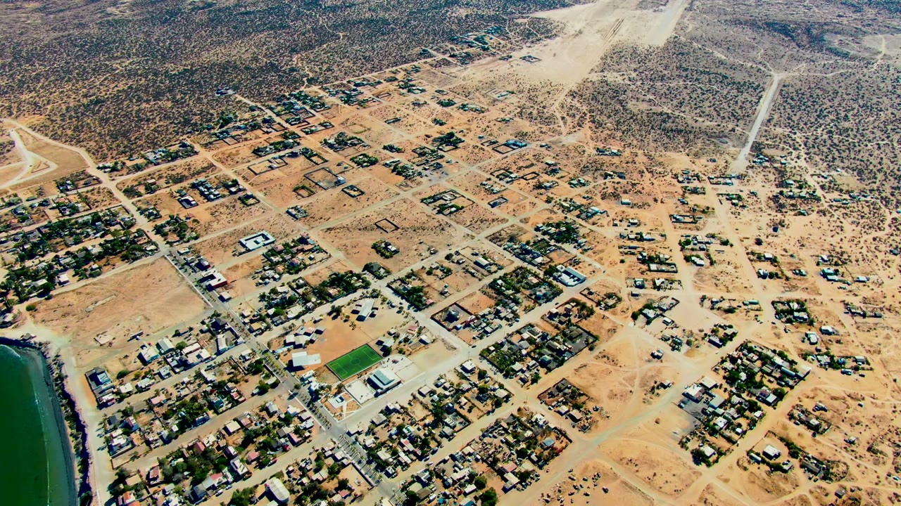 Drone view over sandy residential streets with water still visible on the left.