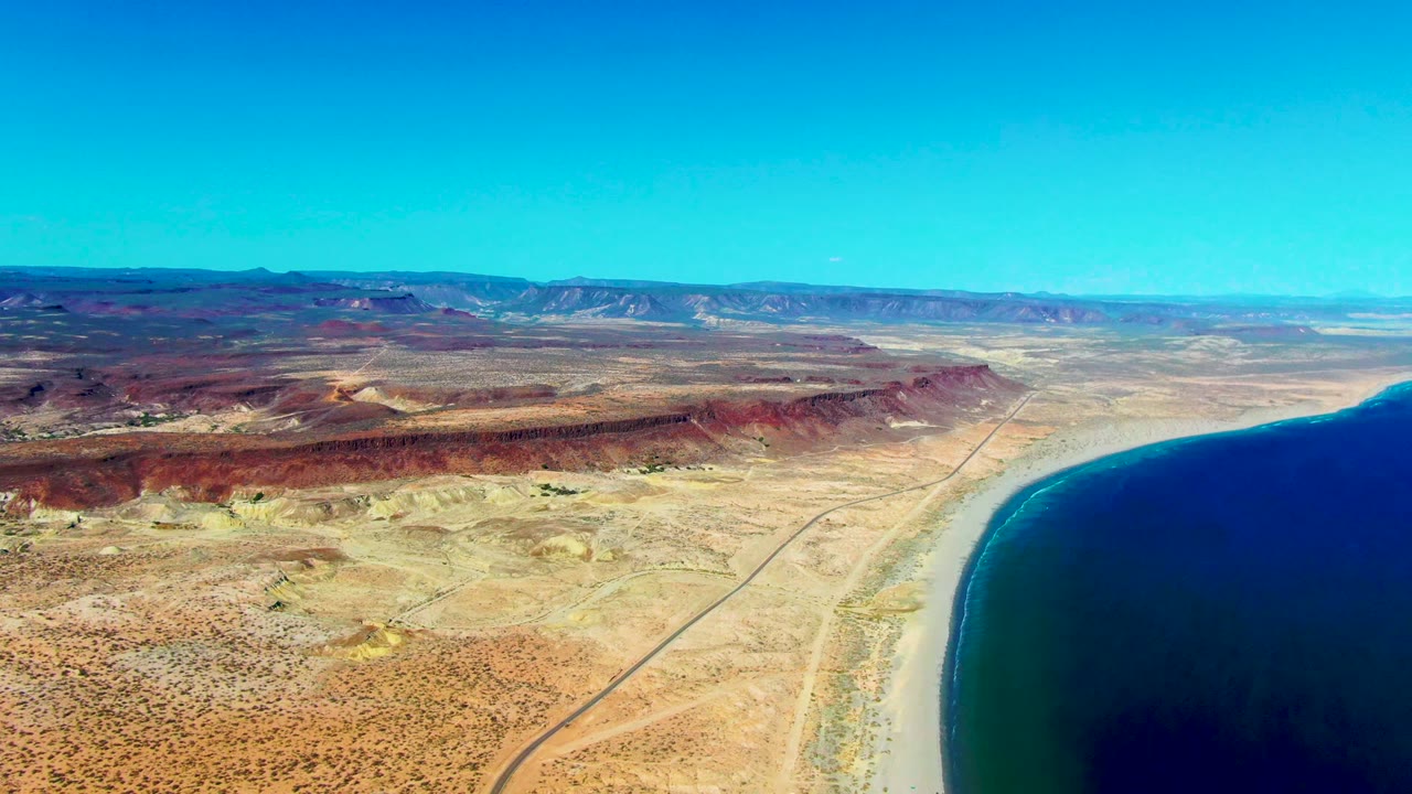 Wide aerial coast with desert road and blue water