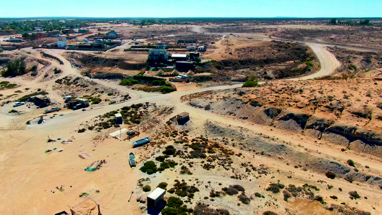 Drone view of intersecting dirt roads in a dry settlement edge.
