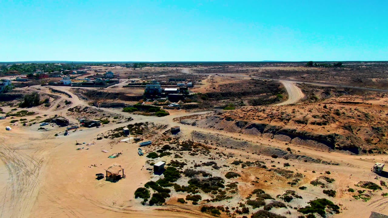 Drone view of sandy road junctions and low earthworks in dry scrubland.