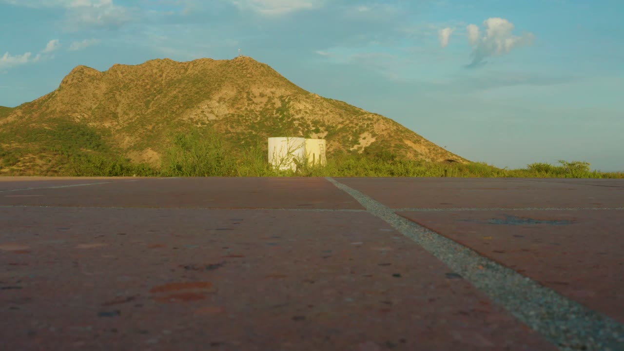 Static paved road foreground with distant mountain and small white structure.