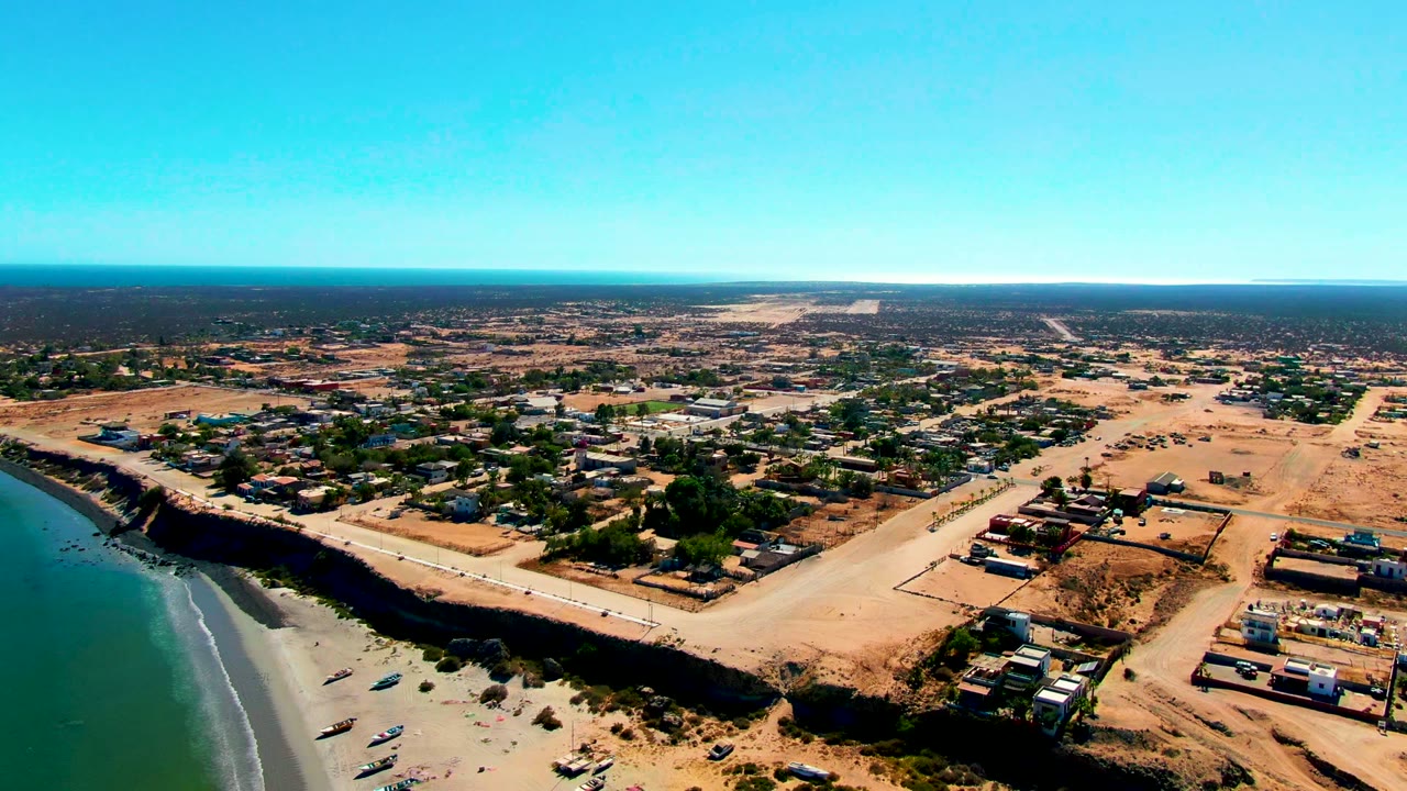 Coastal road and sandy beach seen from above with boats along the shore.