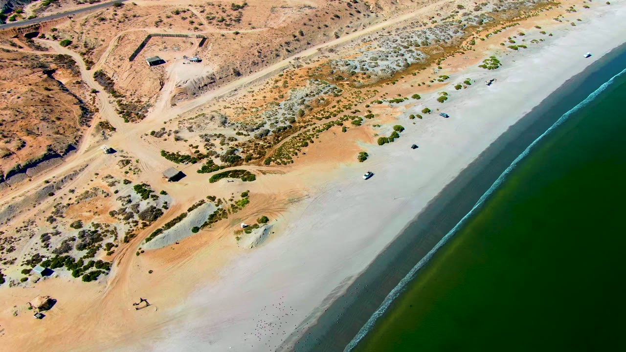 Diagonal shoreline beside dry desert and sparse vegetation.