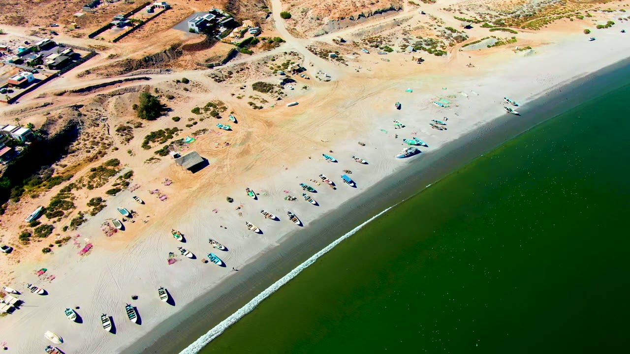 Fishing boats spread across wet sand near the receding shoreline