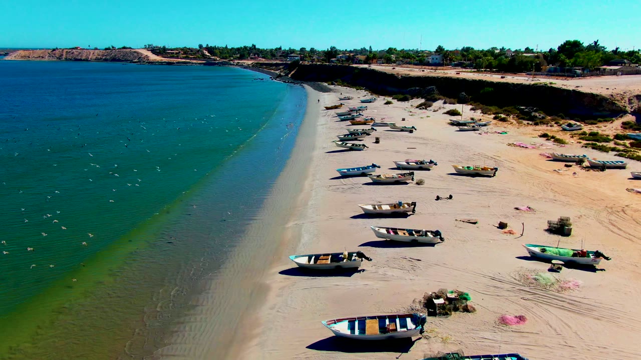 Fishing boats line the sand near a narrow strip of wet shoreline.