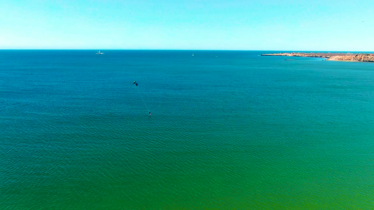 Aerial ocean view with small kites and a distant shoreline