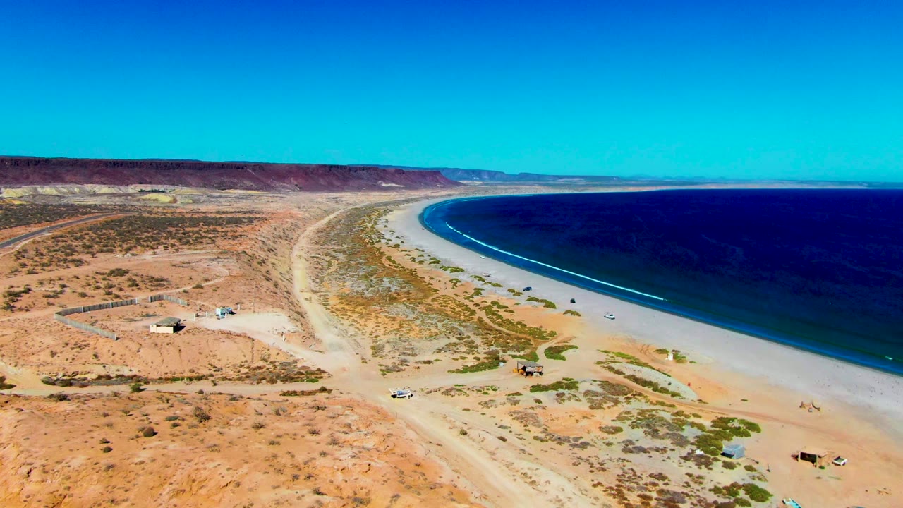 Drone view of arid coast with beach road and waves