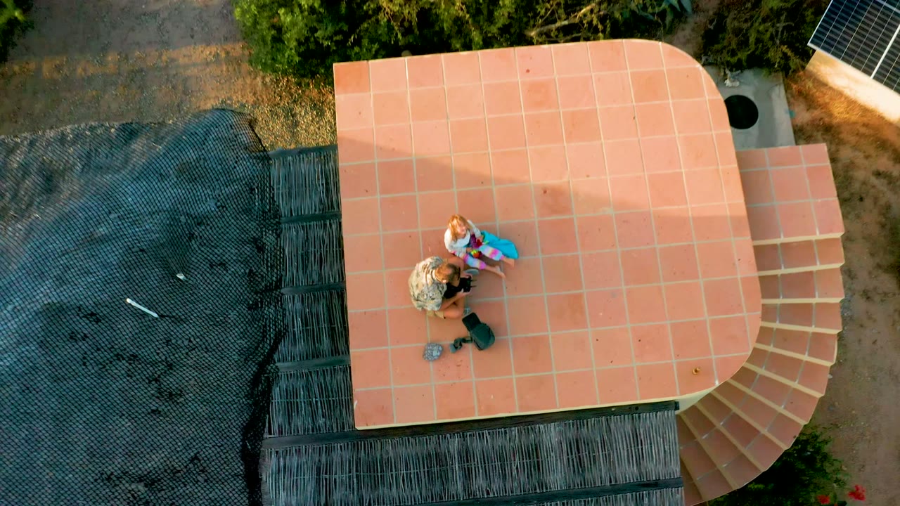 Two people remain on the tiled rooftop as more roof edge is visible.