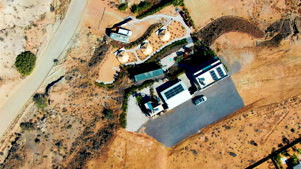 Aerial view of the desert property with the white car still near the driveway.