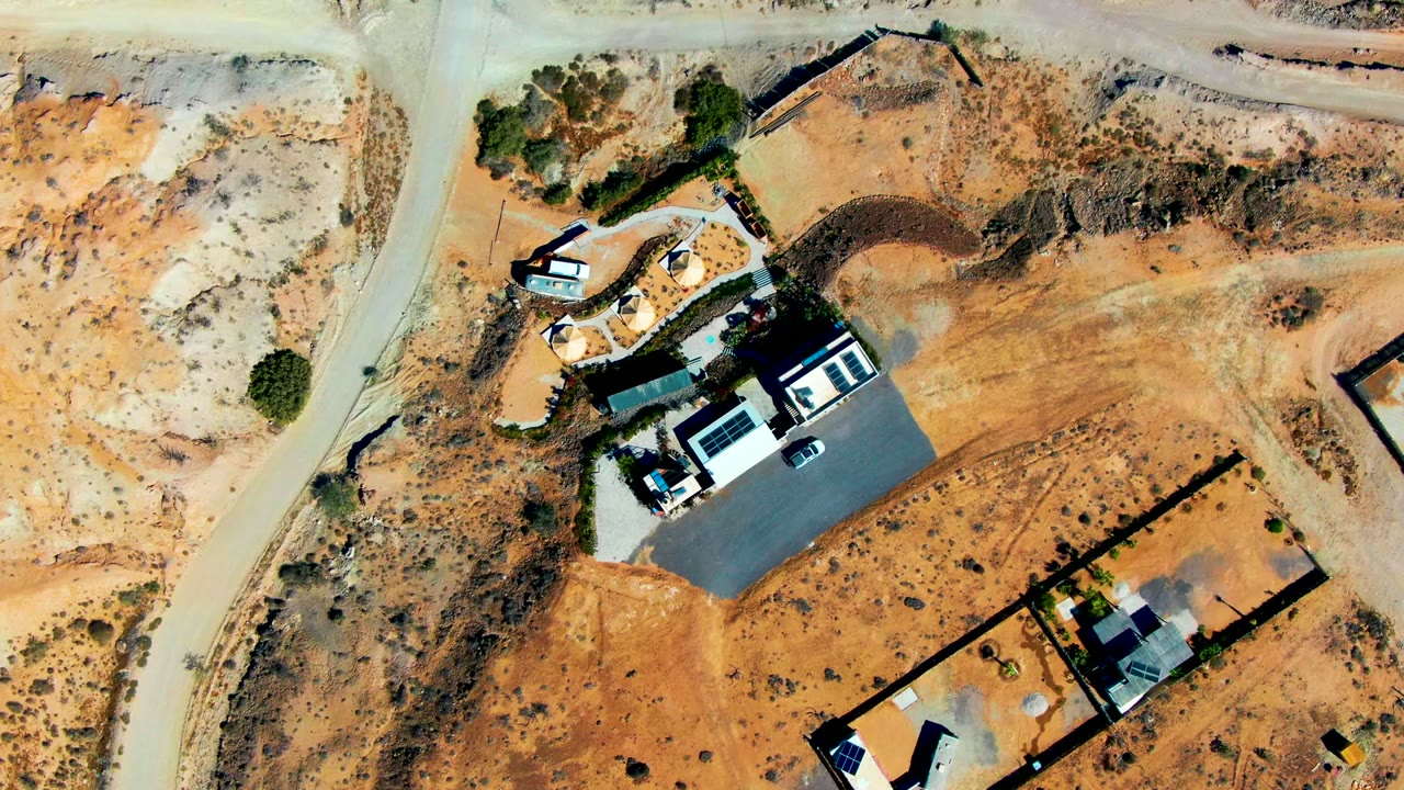 Aerial view of sandy roads around construction buildings and parked vehicles.